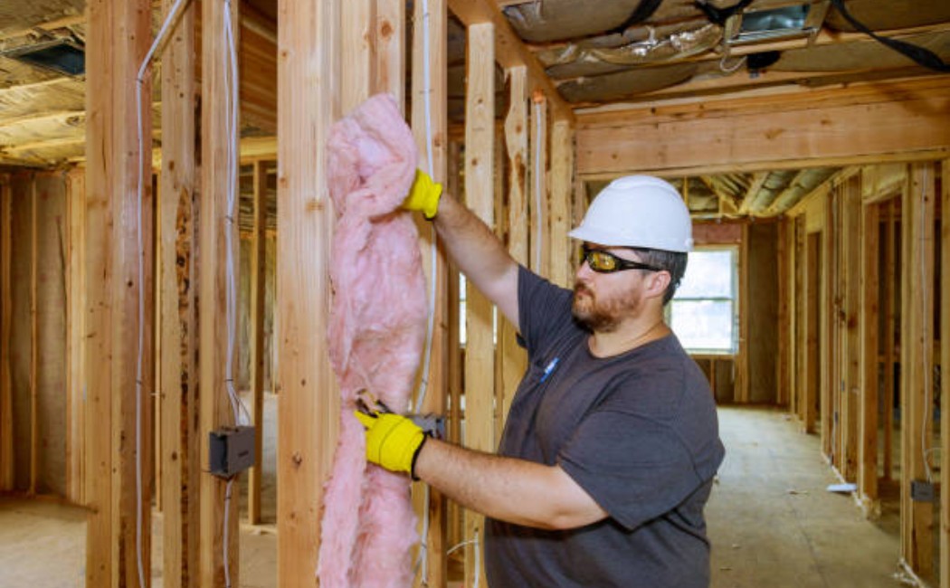 Worker holding mineral wool insulation during wall installation.