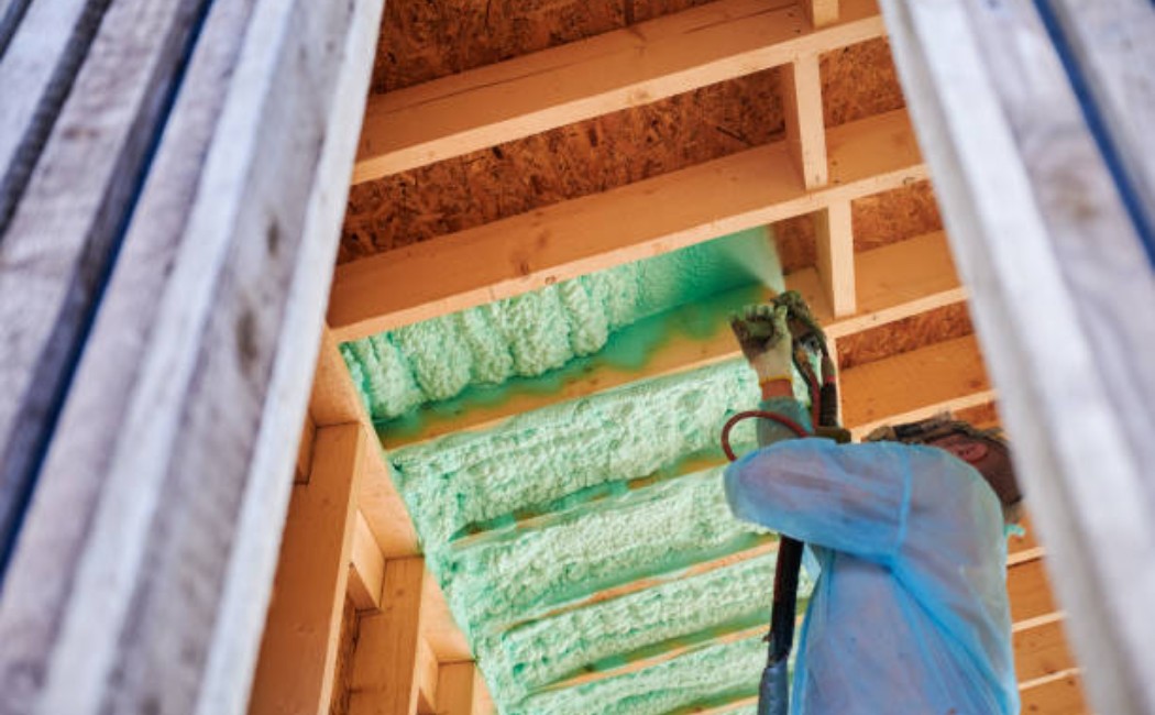 An insulation specialist using spray foam on a wooden wall structure