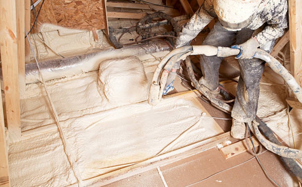 A professional applying spray foam insulation in a home's attic