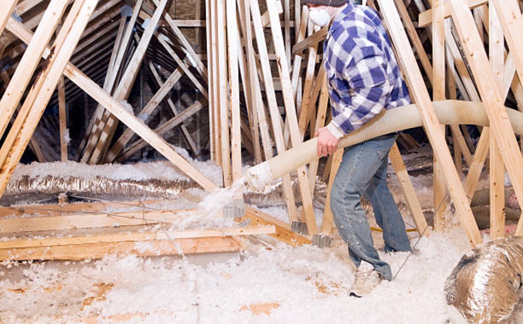 Worker in attic enhancing home insulation with blown material