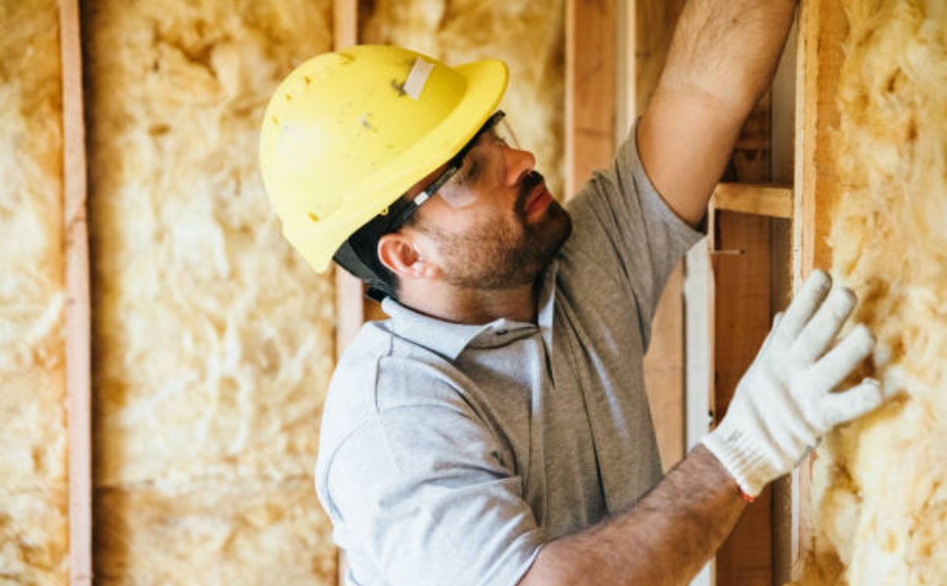 Construction worker fitting insulation in a building wall