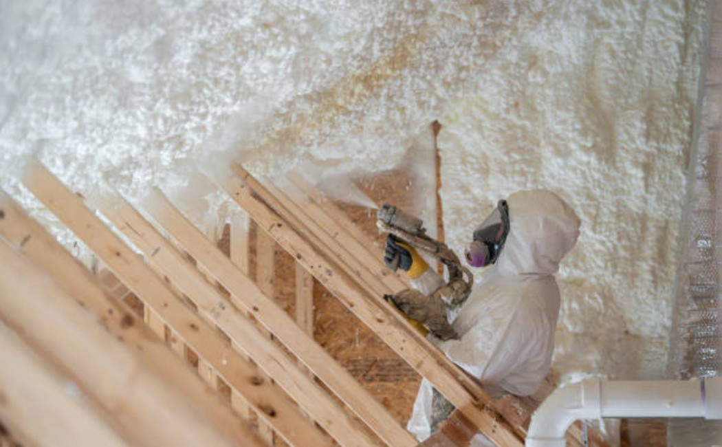 Professional spraying protective insulation on home siding