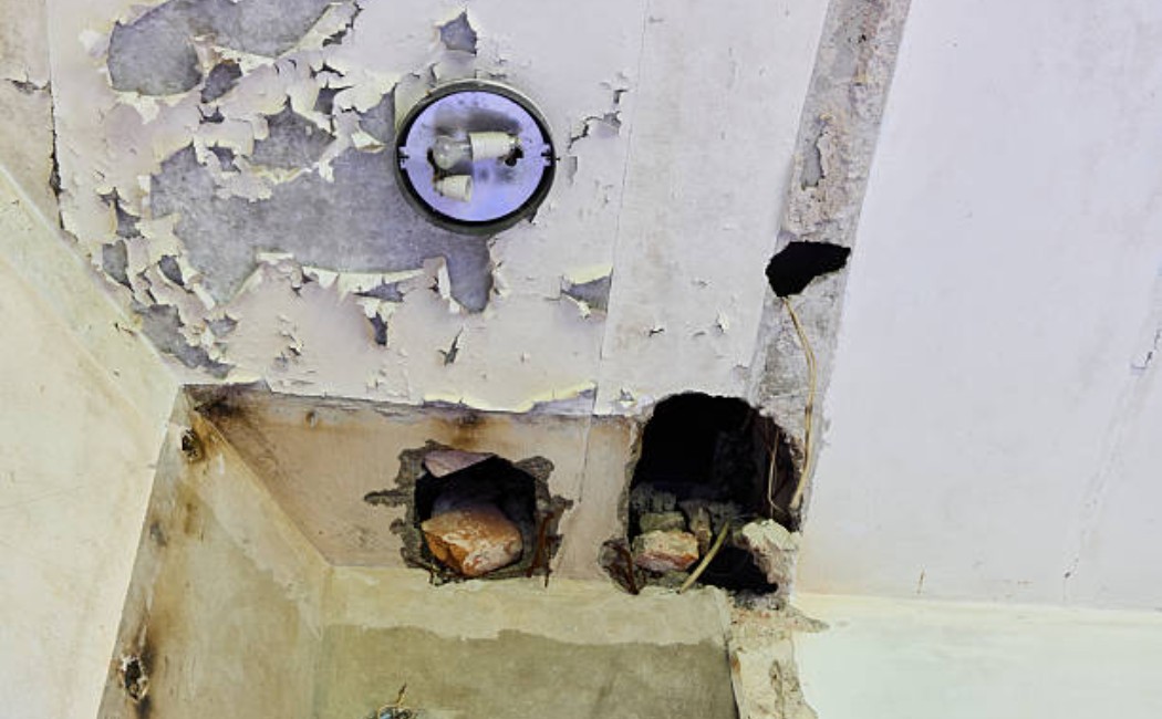 Flaking paint and broken wall around electrical fixtures