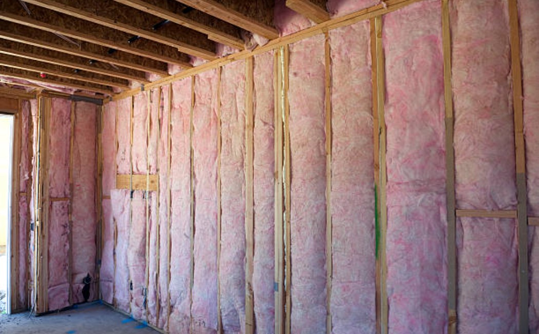Wall of bright pink fiberglass insulation in a house wall cavity