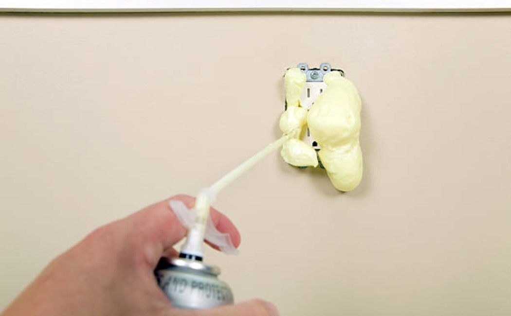 spray foam insulation inside wall outlet area.
