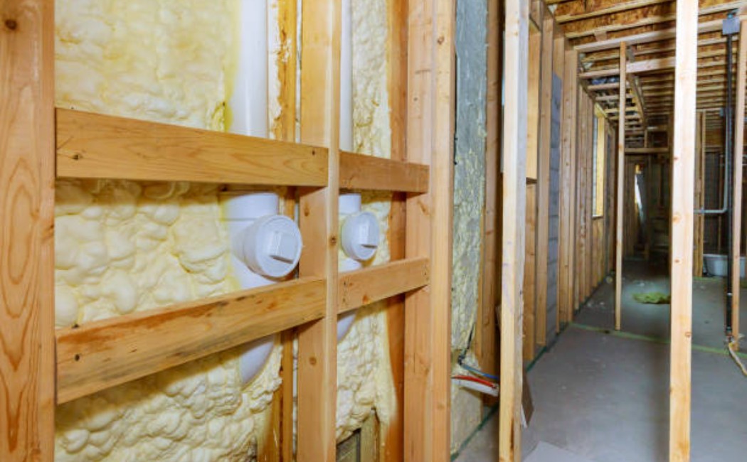 Worker applying spray foam insulation on the basement wall.