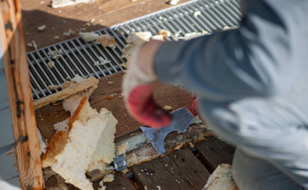 Worker removing old spray foam insulation from the surface