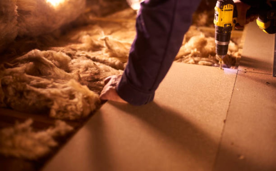 Carpenter installing wooden flooring in the house's attic.